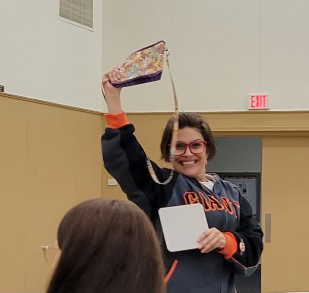 A woman holding up a purse smiling at the camera