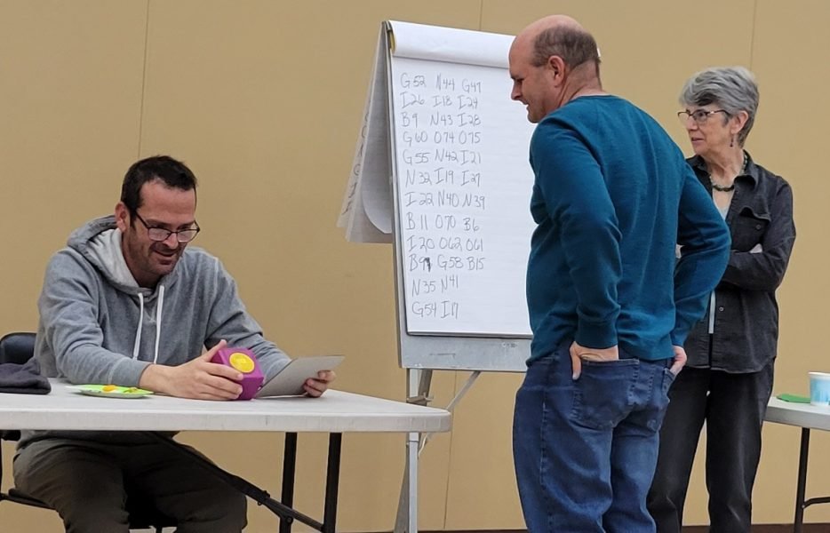 A group of people talking with each other with bingo numbers in the background