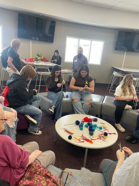 A group of people sitting in a circle knitting
