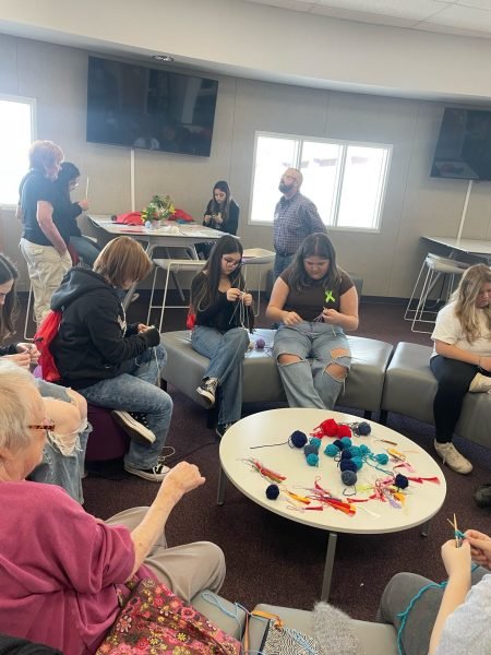 A group of people sitting in a circle knitting