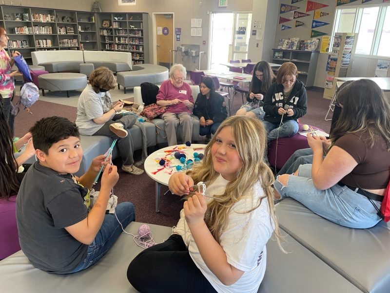 A group of people sitting in a circle knitting