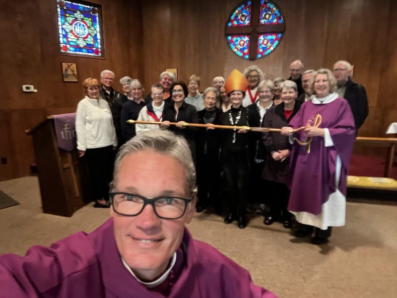 A selfie with the bishop and a large group of people